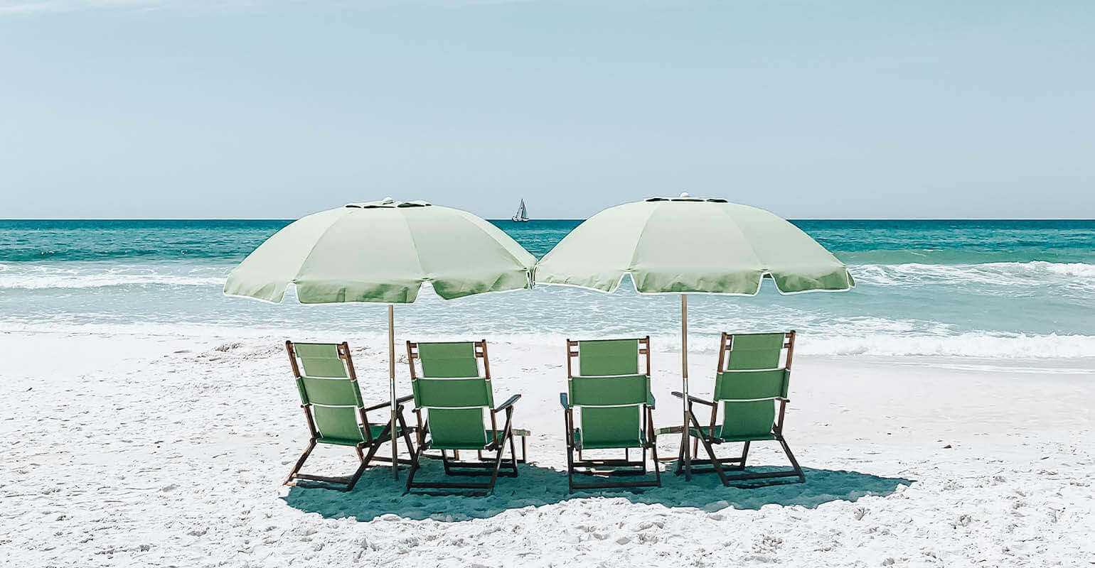 Una chiara foto di sedie verdi sotto ombrelloni su sabbia da spiaggia
