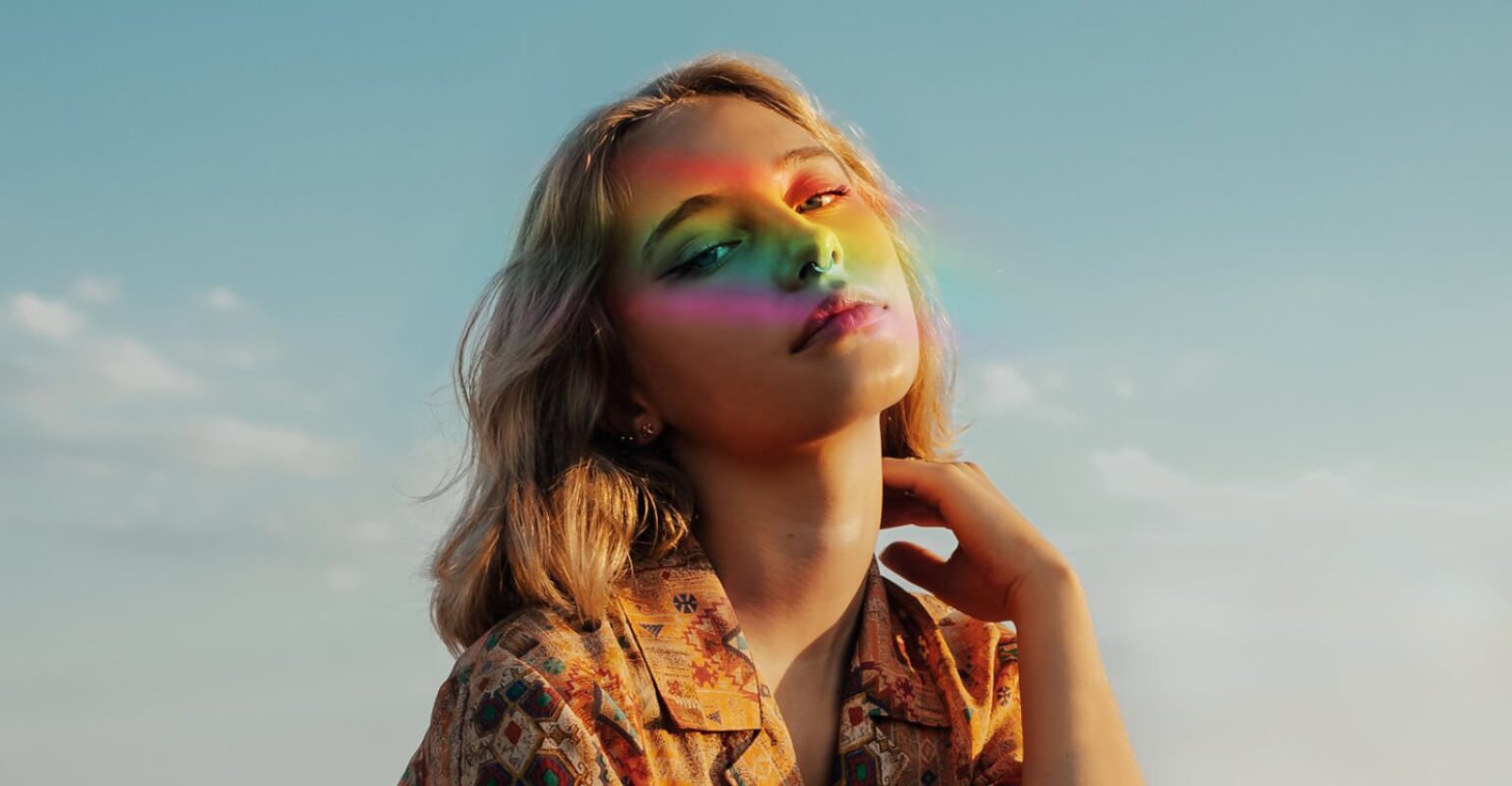 A girl with short hair in a floral shirt with a rainbow filter on her face