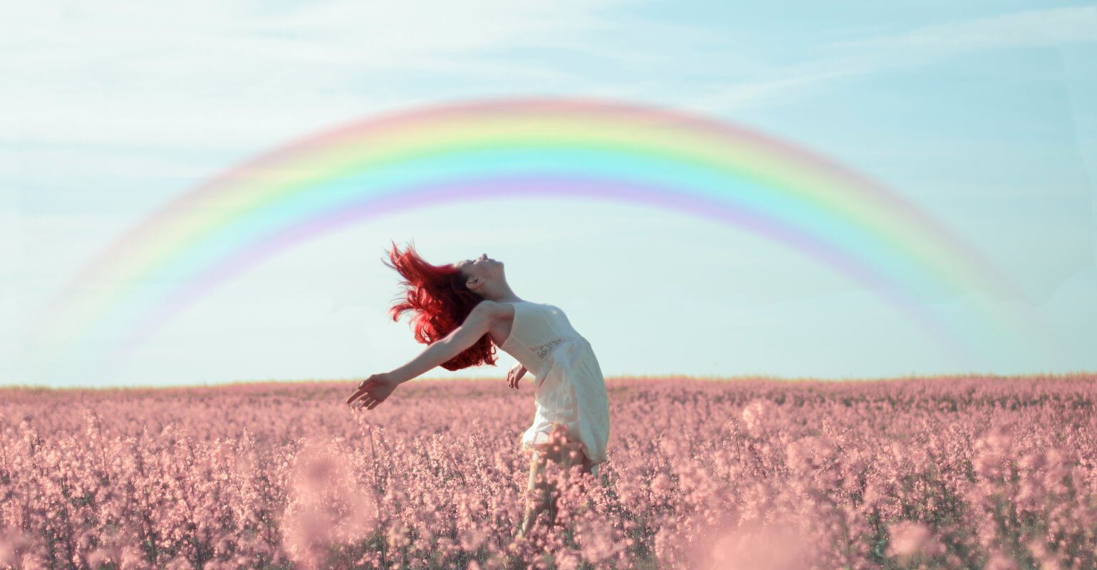 A red haired girl dancing in pink flowers with a rainbow over her head
