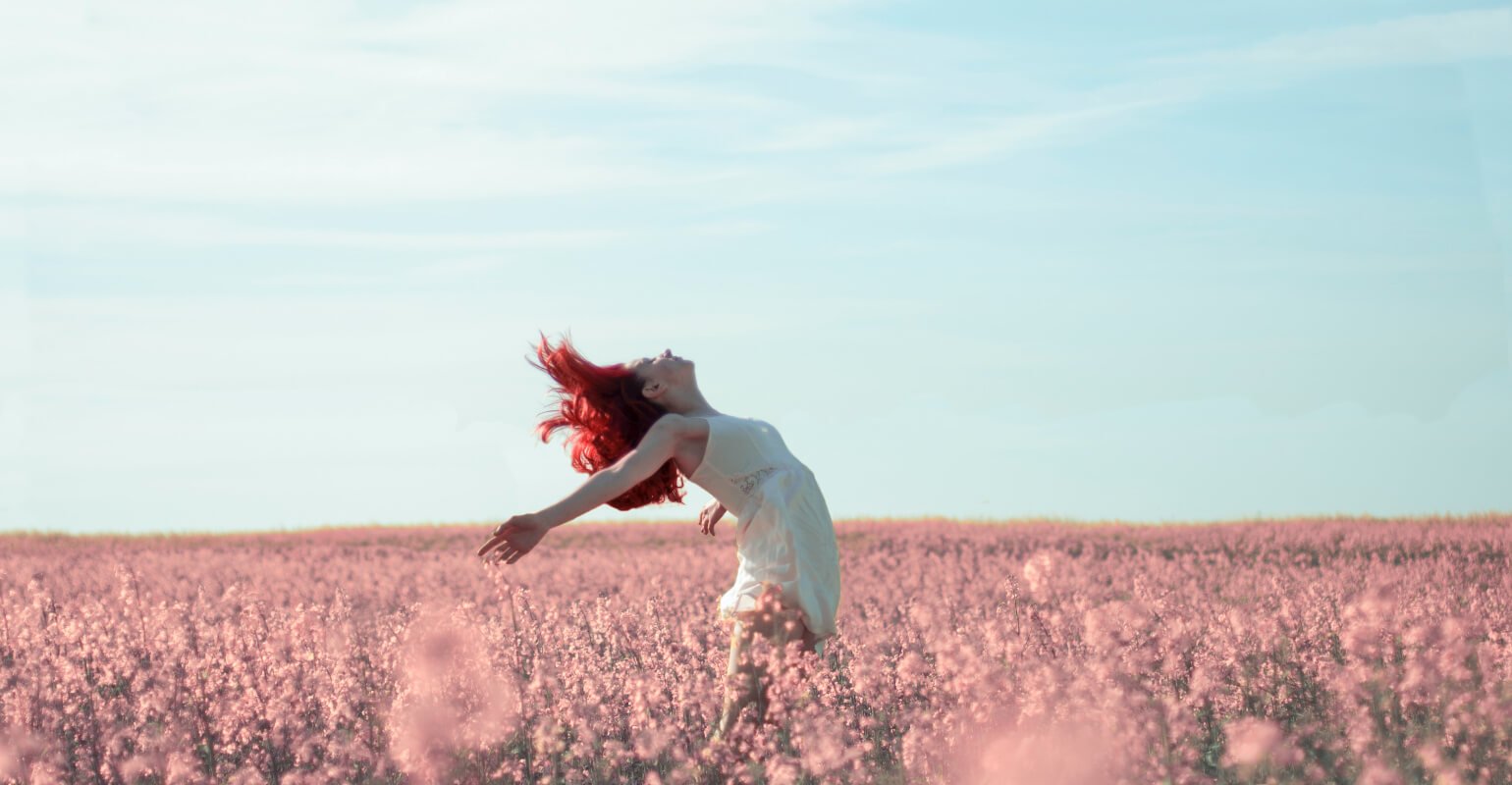 A red haired girl dancing in pink flowers