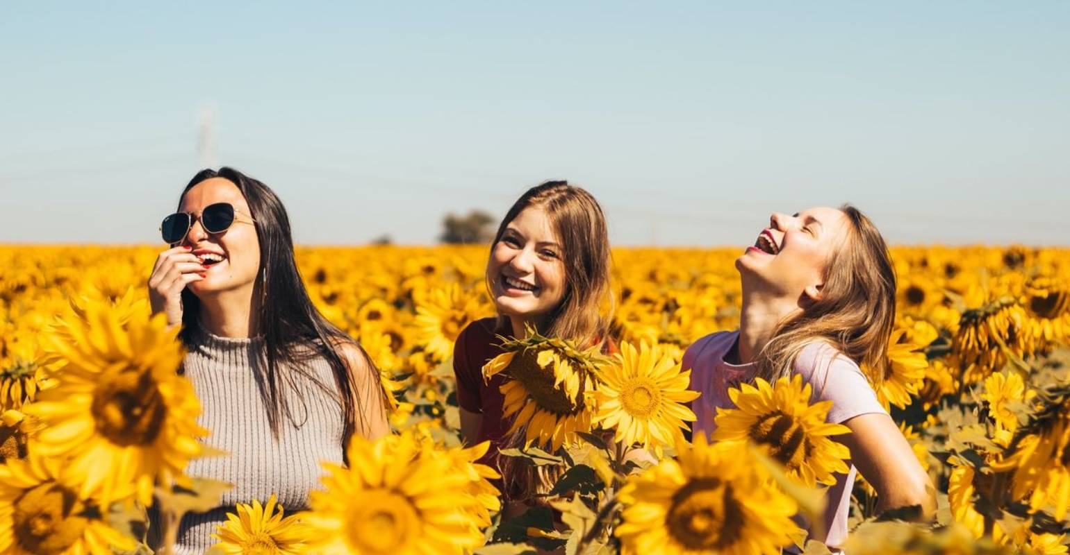 An upscaled and enhanced photo of three women sanding on a sunflower field