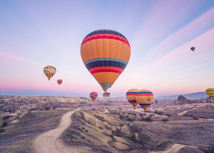Clean, watermark-free photo of hot air balloons over a hilly landscape at dusk, edited with Fotor AI free online watermark remover