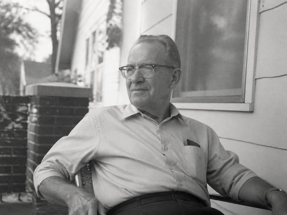 A black and white candid photo of a grandfather sitting on a porch