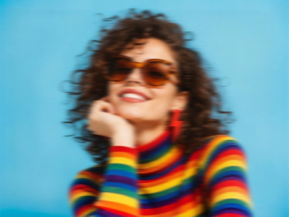 A low resolution image of a curly haired woman wearing a colorful sweater and sunglasses