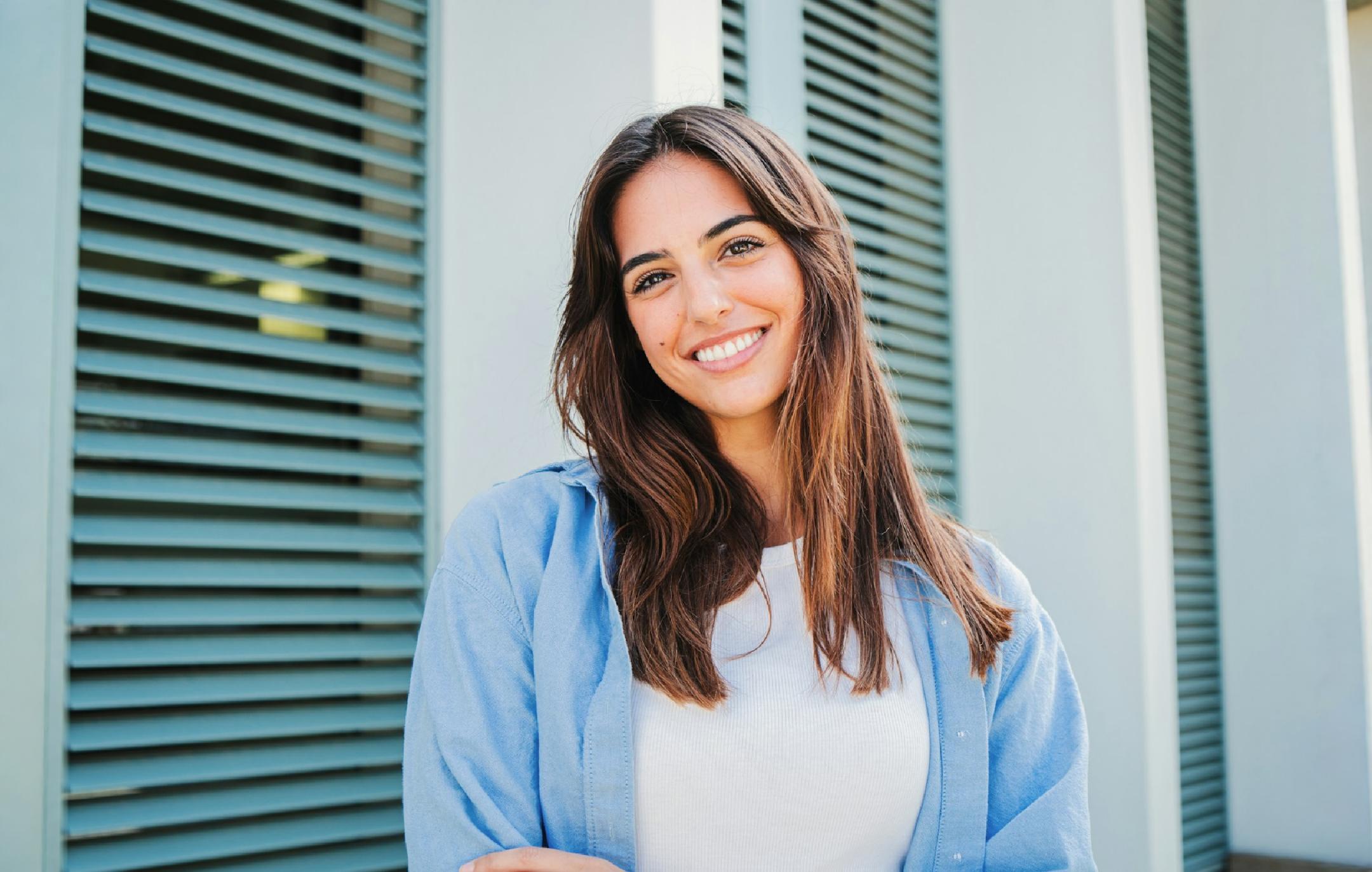 青いシャツを着た女性がカメラに向かって微笑んでいる