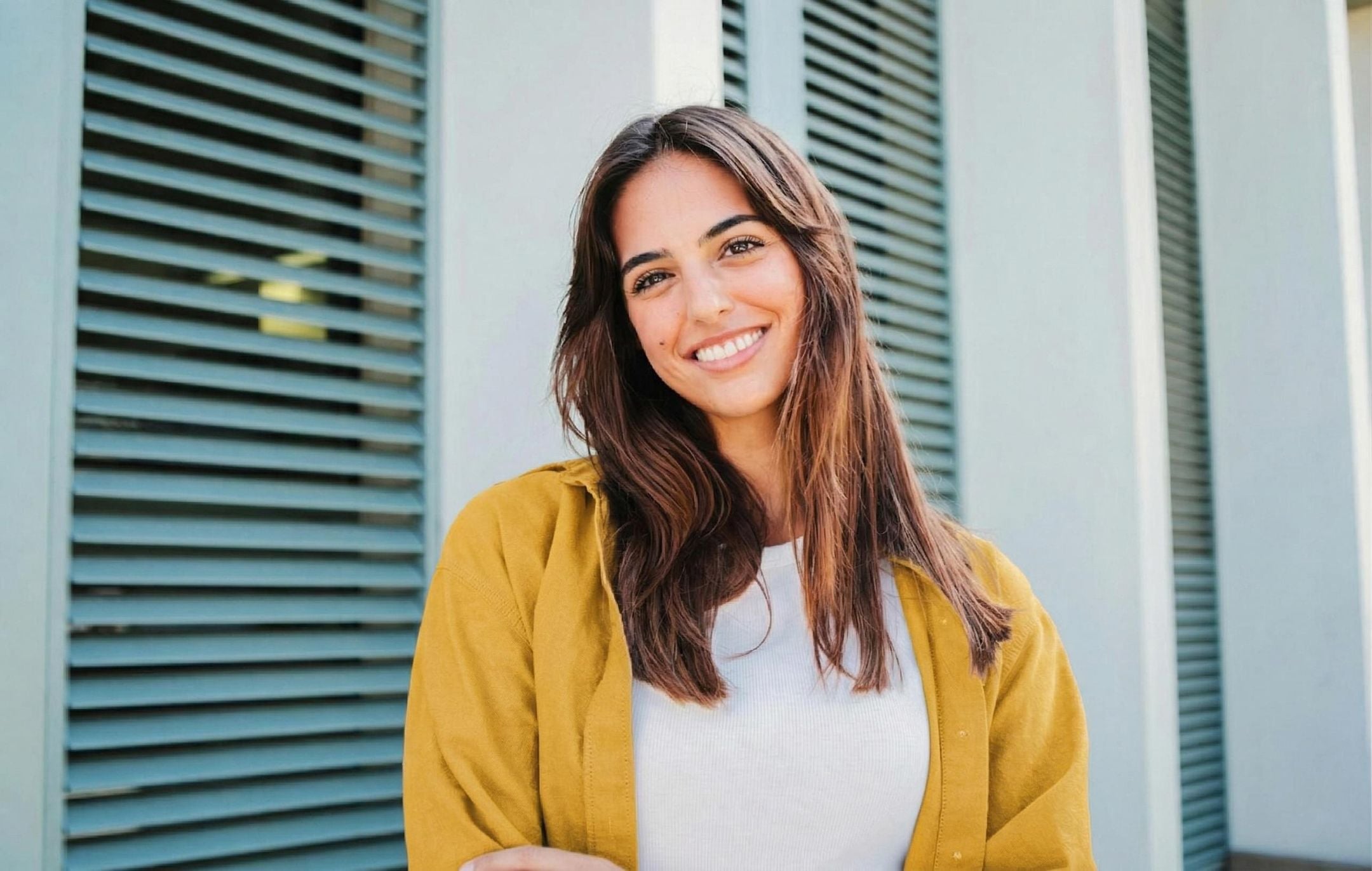 黄色いシャツを着た女性がカメラに向かって笑っている