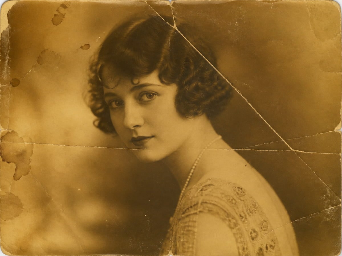 A yellowed and damaged portrait photo of a woman