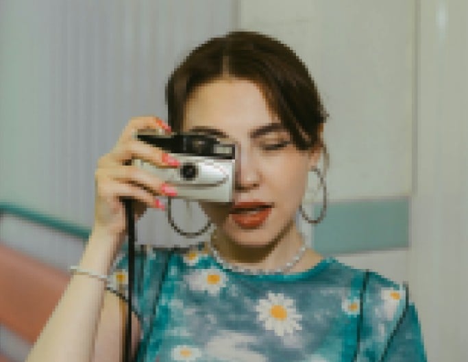 An original pixelated photo of a woman holding a camera
