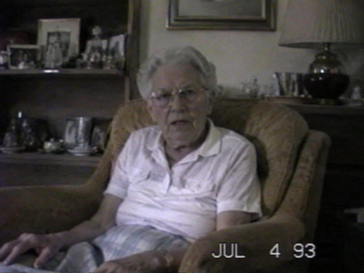Old low quality video of an old man sitting on a sofa
